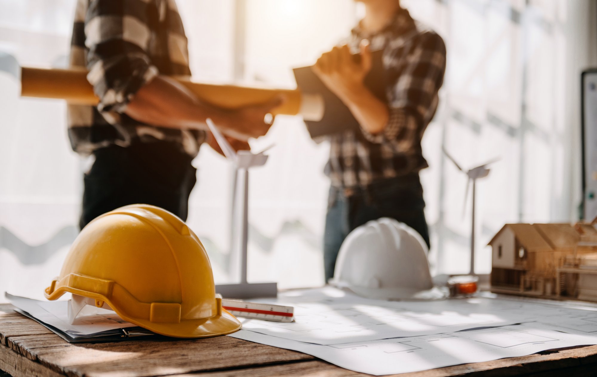 Construction team shake hands greeting start new project plan behind yellow helmet on desk in office to consults about their building project.